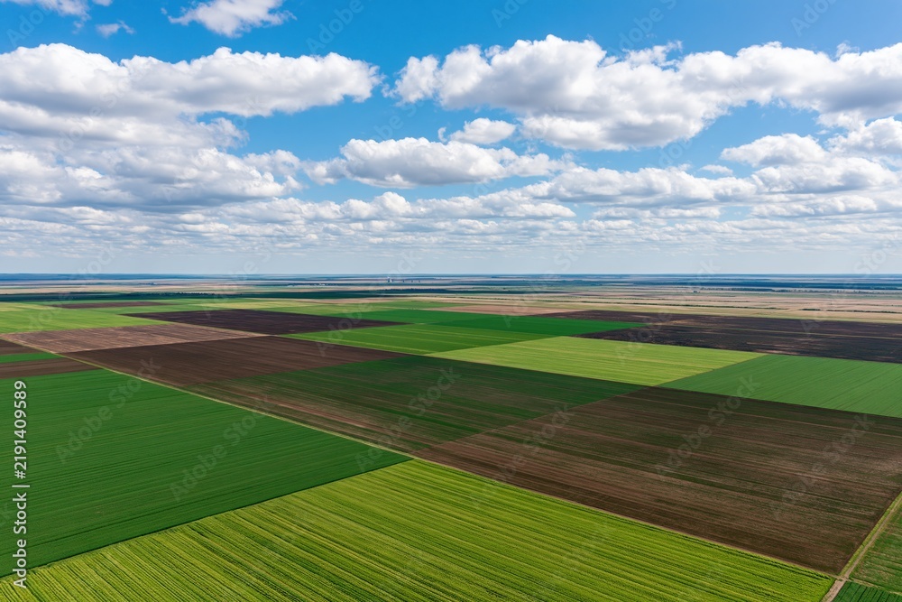 Fototapeta premium The Aerial Farmland Landscape of Colorful Checkerboard Fields and Clouds