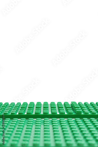 Green LEGO baseplates stacked and arranged on a reflective surface with black background.