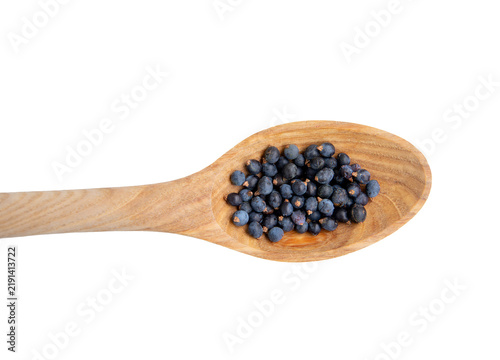 Flat lay view of Juniper, Juniperus communis berries on wooden spoon, isolated against white background. Lot of copy space.