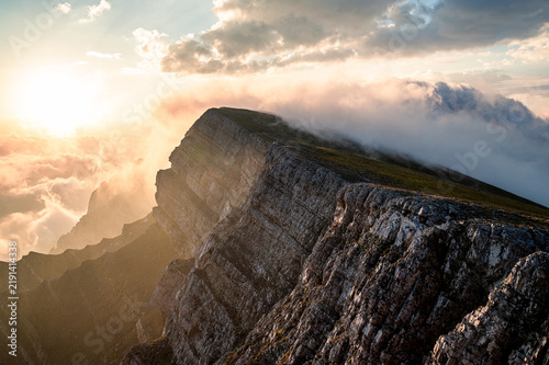 Dramatic mountain ridge at sunrise with clouds and golden sky