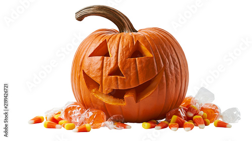 Carved jack-o-lantern pumpkin with candy corn and wrapped orange candies