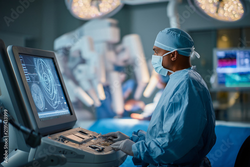 Surgeon using robotic console and joystick controller during precision surgery