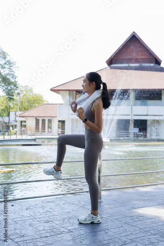 Картината върху платно Young Asian woman wearing sportswear pausing with a towel around her neck, perfo