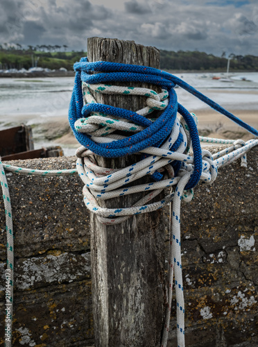 Blue and white mooring lines looped around a wooden post