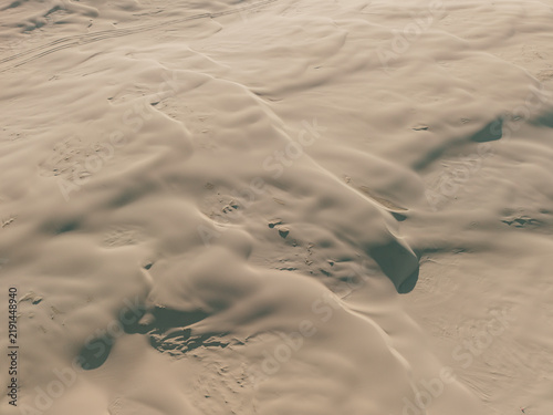Aerial view of the vast sand dunes at Birubi Point with undulating patterns and soft shadows in the late afternoon light in Anna Bay, New South Wales, Australia.