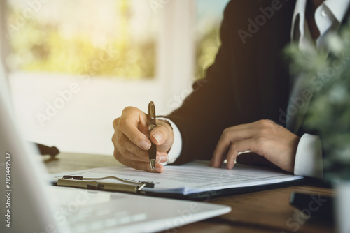 Lawyers reviewing and signing a legal contract at a desk with a gavel and scales of justice, representing legal consultation, agreement process, and professional law services.