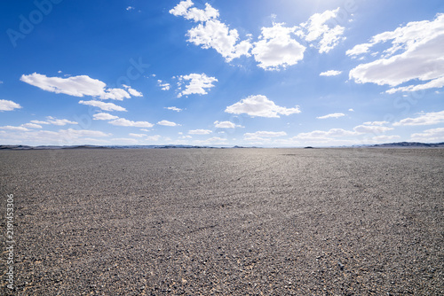Bild auf Leinwand Vast gravel desert plain under a clear blue sky with white clouds in Xinjiang, C