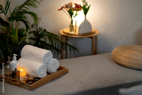 Spa Room Setup with Rolled Towels Candle and Oil Bottles on Wooden Tray