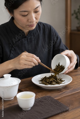 Tea taster examining brewed leaves beside a cup