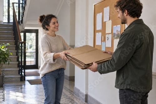 Neighbors exchanging flattened cardboard in a hallway