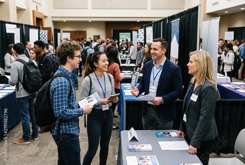 Students gather around booths at a career fair location on campus. They talk to recruiters and ask questions about job opportunities. It is spring, and many are seeking internships