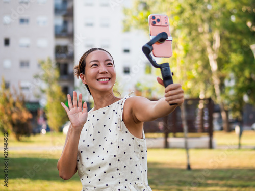 Modern mobile videography concept featuring a cheerful woman creating stabilized selfie footage with a smartphone stabilizer.