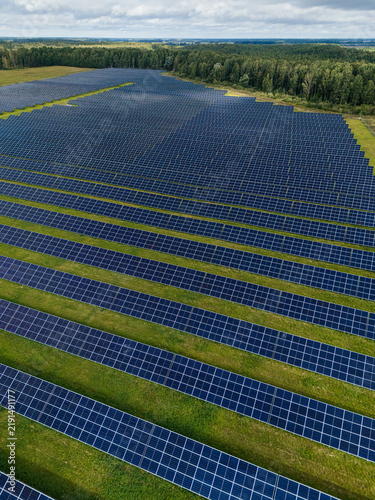 Aerial view of solar panel rows on green grass, photovoltaic farm generating renewable electricity 