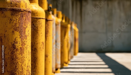 Old rusty yellow gas cylinders lined up in a row.