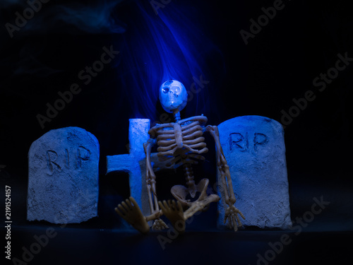 Skeleton in Halloween cemetery blue smoke black background