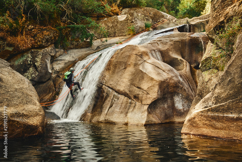 Cuadro en lienzo Canyoning adventurer rappelling down a steep waterfall into a dark pool