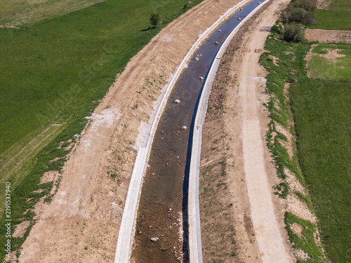 Fotografie Aerial view of a river restoration project with flood embankment and channel widening taking place near green fields and a dirt path