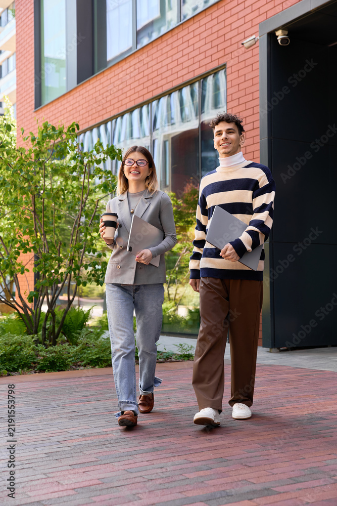 Fototapeta premium Young coworkers enjoy a sunny day outside their modern office building