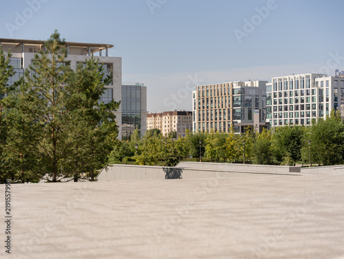 Obraz na plátne Modern residential buildings rising behind a row of green pine trees in Astana, Kazakhstan