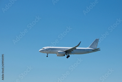 Foto White Commercial Passenger Airplane in Clear Blue Sky on Landing Approach