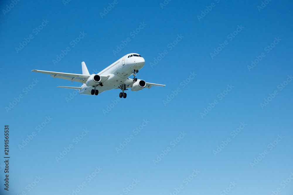Obraz premium White Commercial Passenger Airplane in Clear Blue Sky on Landing Approach