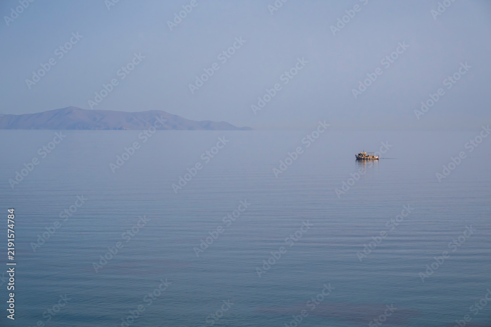 Fototapeta premium Small fishing boat on calm sea off Lotos Beach, Syros, Greece 