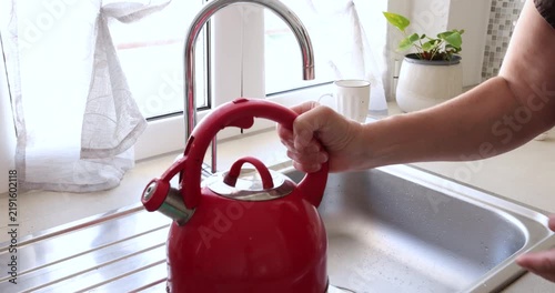 Closing red kettle lid inside kitchen. Modern domestic household culinary preparation. Cozy morning routine cooking lifestyle.