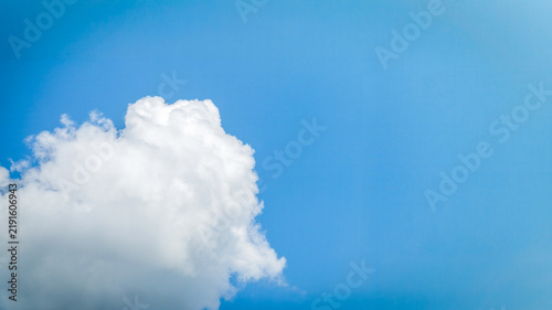 Fluffy white cloud in the clear blue sky. Natural background.