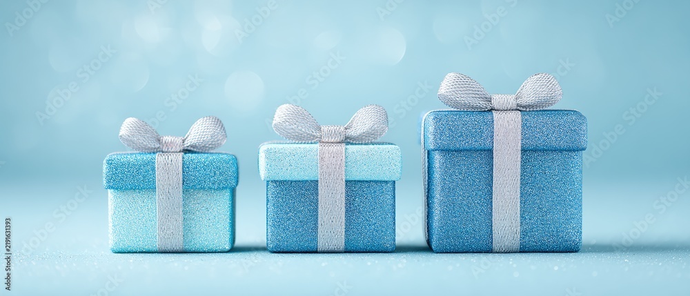 Fototapeta premium Three shimmering blue gift boxes adorned with elegant ribbons set against a soft blue backdrop ideal for holiday festivities birthdays or any special celebration creating a joyful and festive ambiance