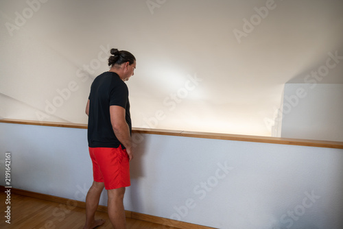 фотографія Man in red shorts looking down from balcony