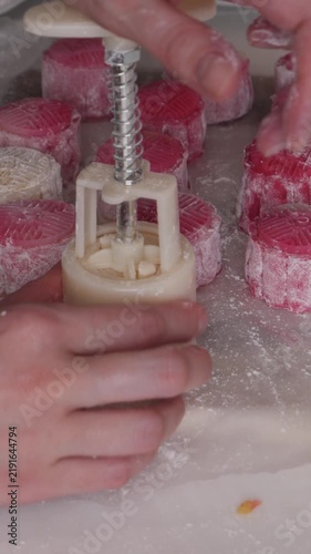 Homemade pink and white snow skin mooncakes with floral mold patterns, a no-bake Mid-Autumn Festival treat dusted with flour on a kitchen table.