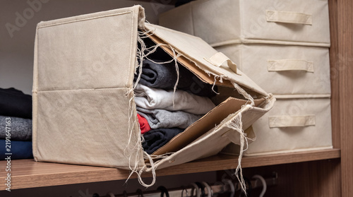 Damaged fabric storage box with torn lid, showing neglected clothing storage in a worn out closet organizer