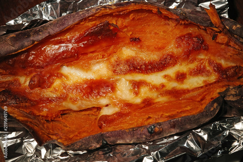 Foto roasted sweet potato filled with melted gooey cheese wrapped in foil cozy winter