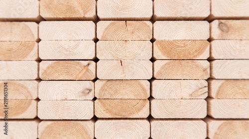 Neatly stacked light pine lumber planks forming a symmetrical pattern for construction projects