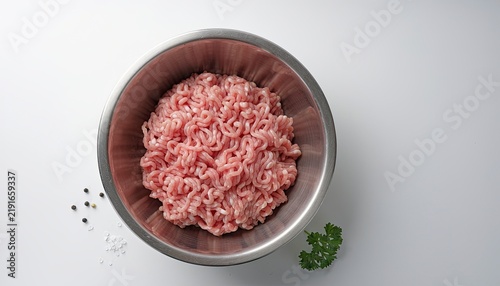 Raw Ground Meat in Metal Bowl: A close-up overhead view of raw, pink ground meat, likely pork or chicken, piled high in a stainless steel mixing bowl.