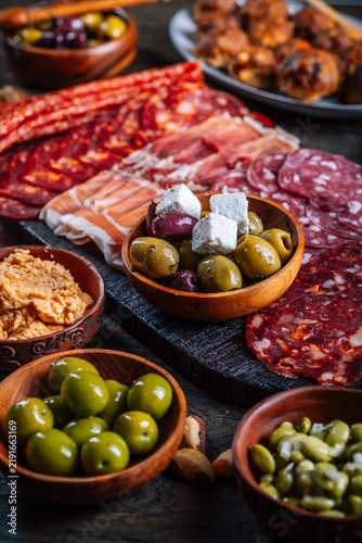 Assortment of cured meats and antipasti served on a rustic wooden board