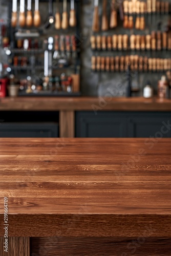 Rustic wooden table top with blurred artisan workshop background in studio
