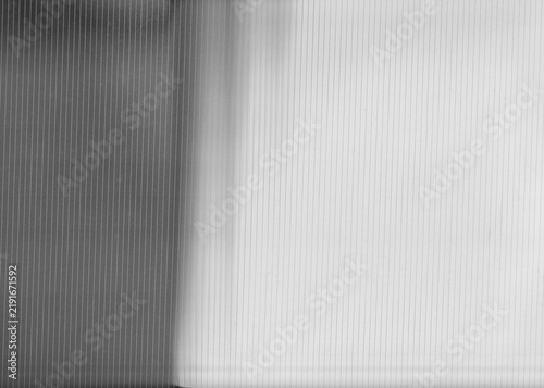 Vertical parallel reeded glass lines create a translucent corrugated texture across a split light and dark monochromatic background surface.