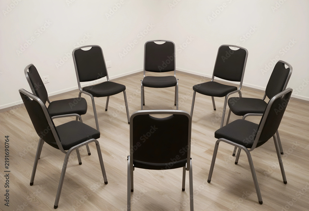 Fototapeta premium Group therapy and support circle, empty chairs arranged in a ring for counseling session or corporate team meeting in a minimalist room with wood floor