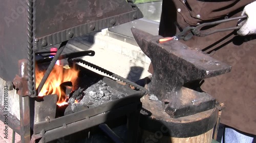 Blacksmith work close up, bending hot metal bar, two takes.