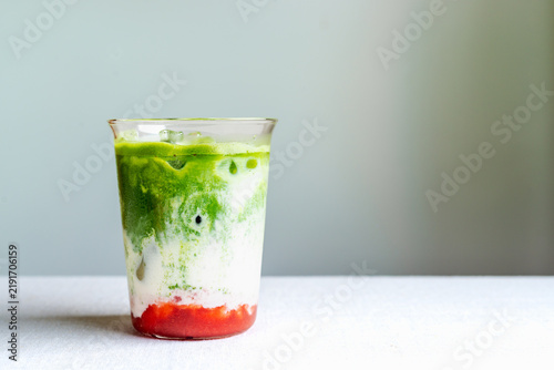 Layered iced strawberry matcha latte in glass with copy space.