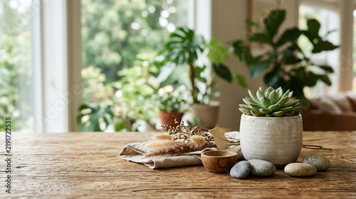 A serene tabletop arrangement featuring a succulent in a ceramic pot, dried grasses, a small wooden bowl, and smooth river stones
