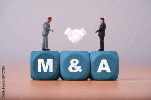 Mergers and acquisitions concept with businesspeople and handshake symbol on M and A blocks represent corporate merger, acquisition partnership, negotiation deal and business integration strategy.