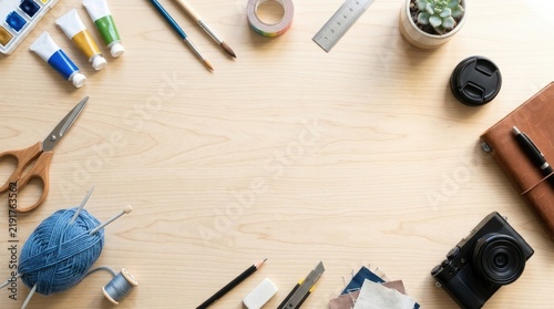 A light-colored wooden table displays a variety of art supplies.