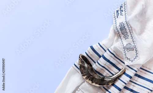 Shofar across tallit, Yom Kippur greeting concept. Jewish holiday banner with tallit and shofar