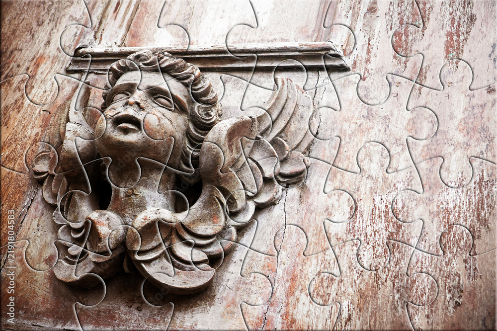 Fototapeta premium SCULPTURE OF AN ANGEL ON A WOODEN DOOR - The slow faith building or loss - Faith building or loss concept in jigsaw puzzle shape