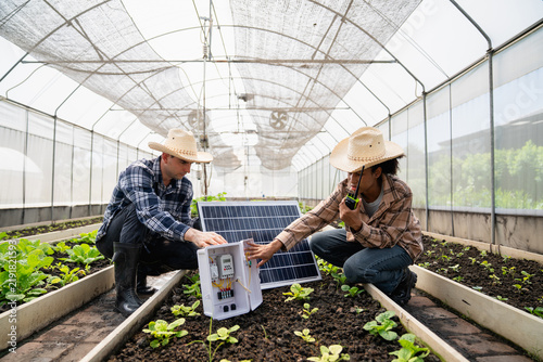 Two farm technicians wiring a solar panel's control box in greenhouse