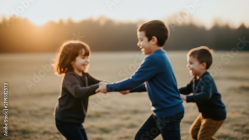 Happy children playing and holding hands in a field during sunset golden hour.