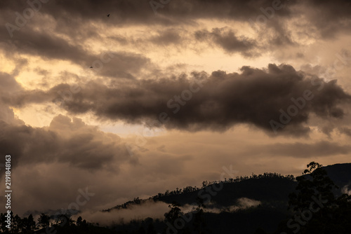 Dark storm clouds gather above mist-covered hills in Sri Lanka's central highlands, creating a moody mountain landscape before rainfall.