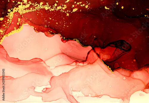 Abstract red and gold alcohol ink background texture featuring fluid marble paint mixing with glowing golden foil glitter dust particles